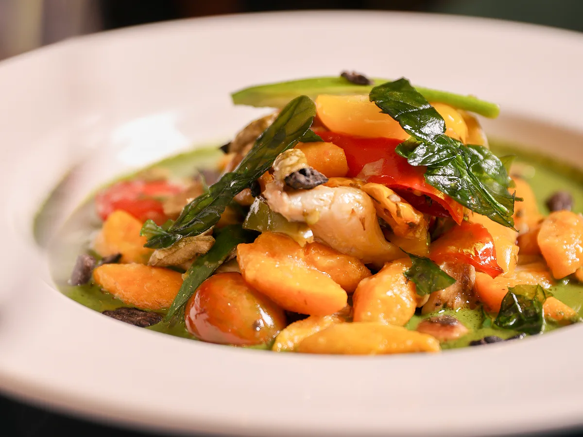 Foto de Gnocchis de butternut con tomate cherry, champiñones ostras pimientos asados sobre coulis de albahaca y crocante de aceitunas