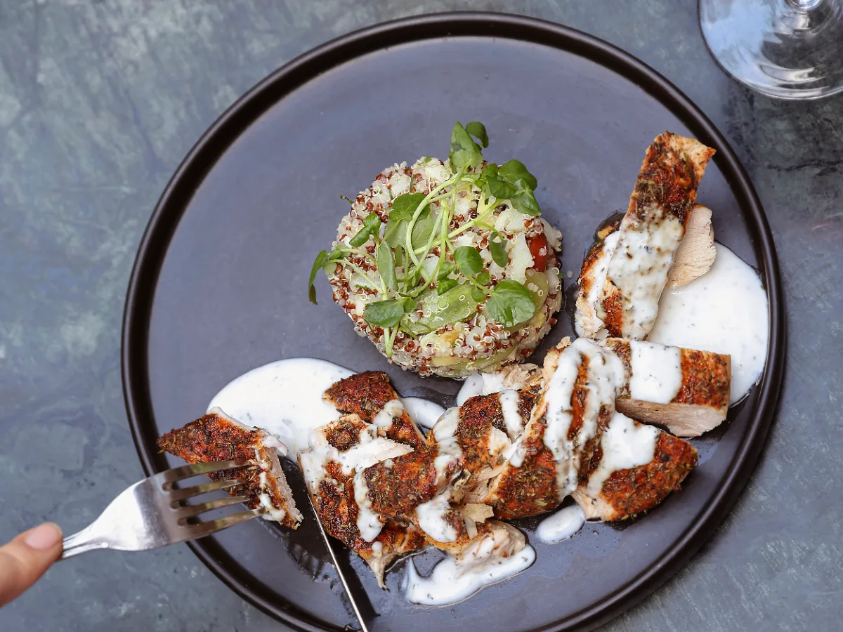 Foto de Filetitos de pollo con especies y aderezo de yoghurt y romero acompañado de timbal de quinoa, palmitos, palta y tomate cherry