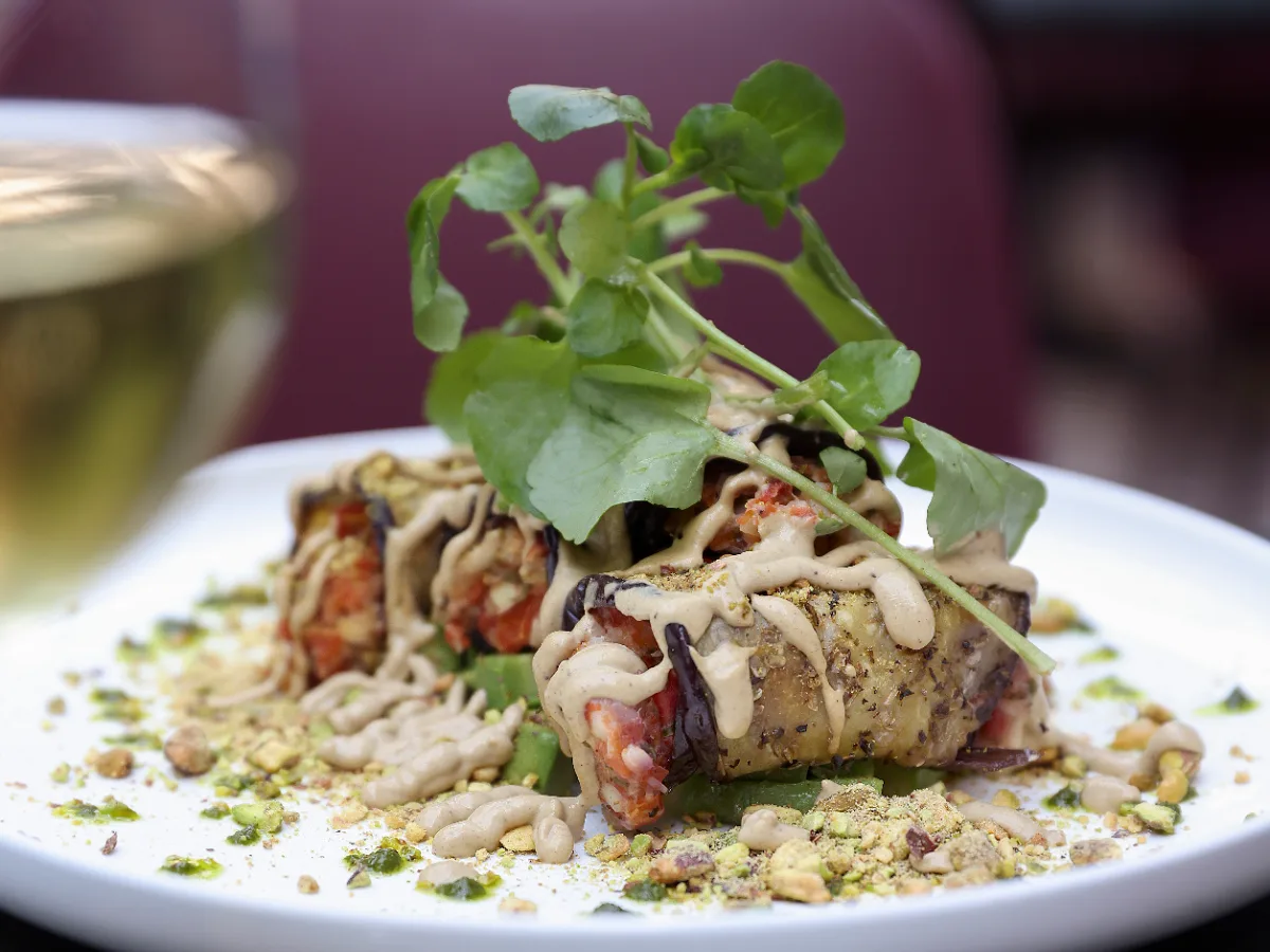Foto de Rollitos de berenjena a la plancha rellenos de palmitos y tomates confitados sobre cama de palta y salsa de pistachos
