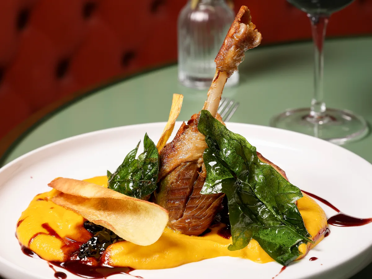 Foto de Confit de canard con puré de zapallo y zanahoria asado al aroma de drambuie y salsa de berries